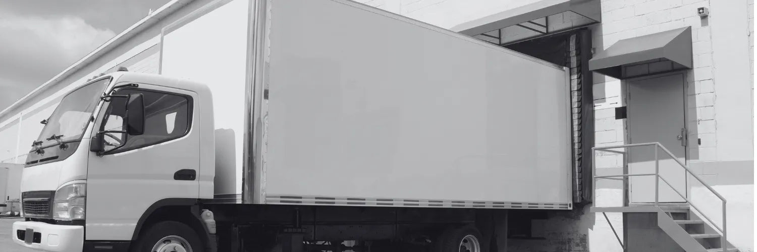 White delivery truck parked in front of a building with a staircase.