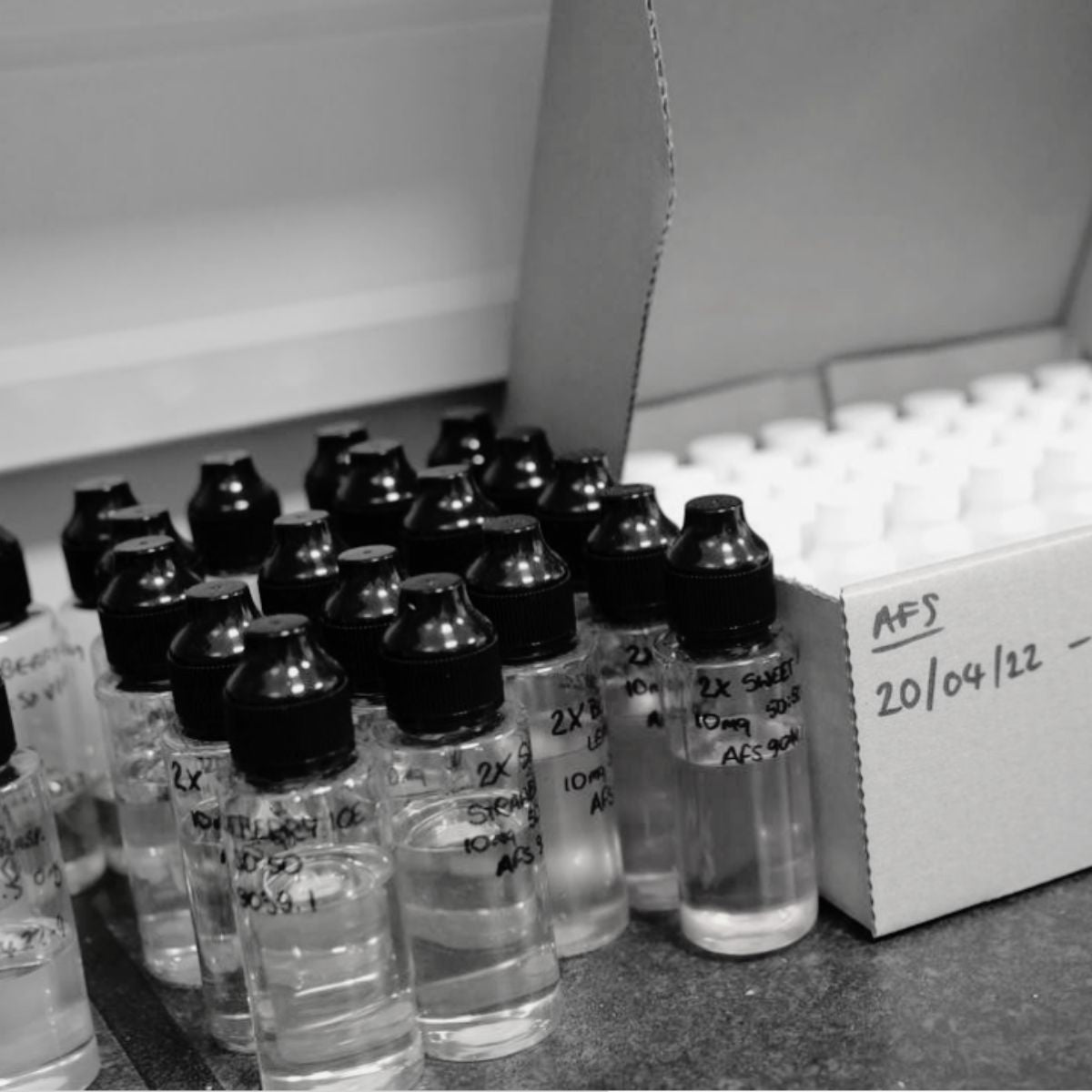 Collection of labeled vials on a table with a box in the background