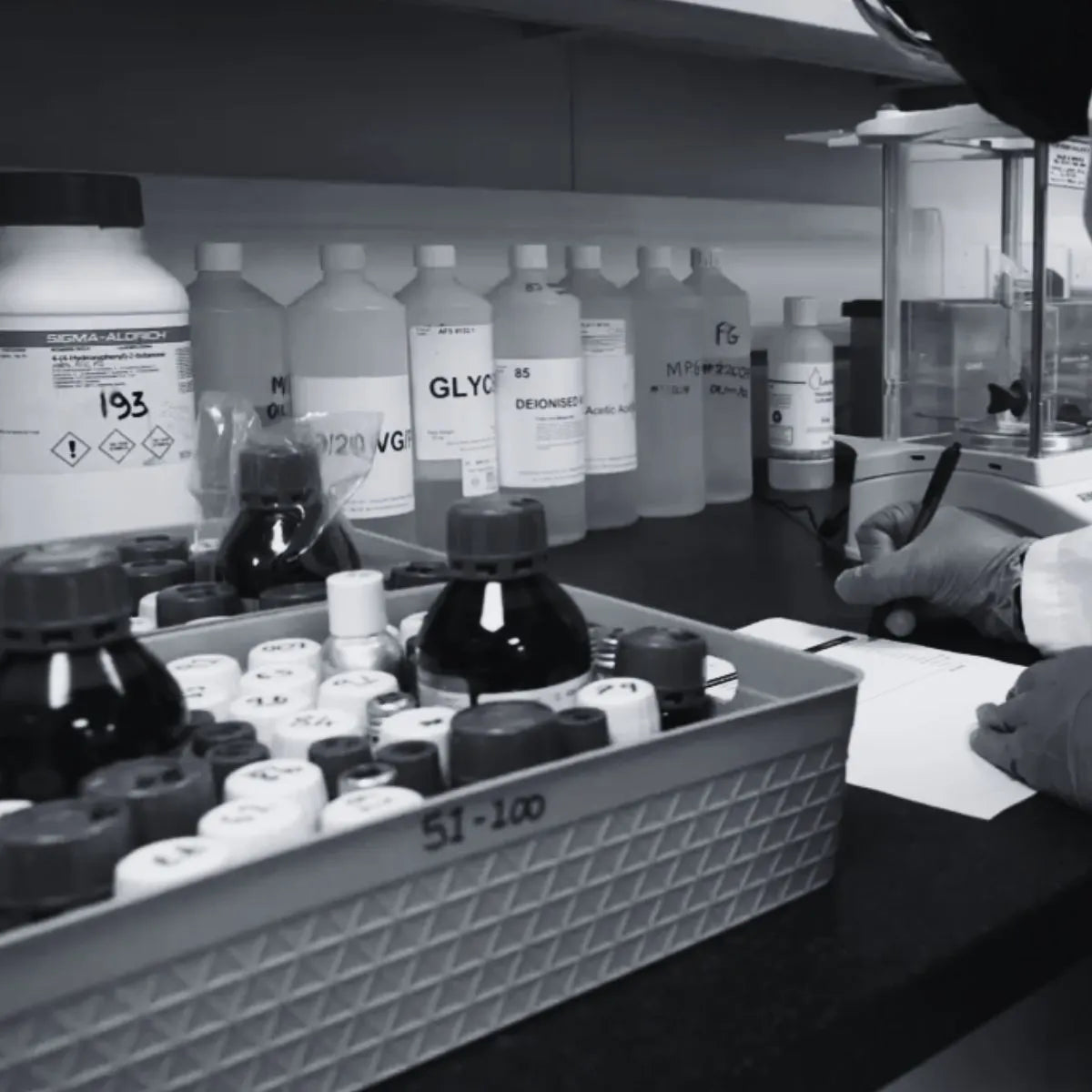 Laboratory setting with various bottles and a person wearing gloves.