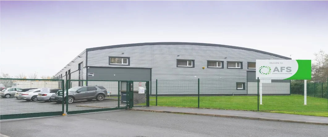 Modern industrial building with a green sign displaying 'AFS' on a clear day.