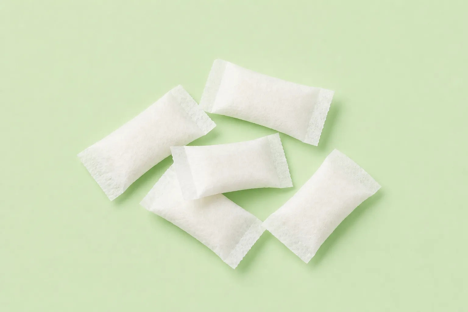 Loose nicotine pouches on a pastel green background